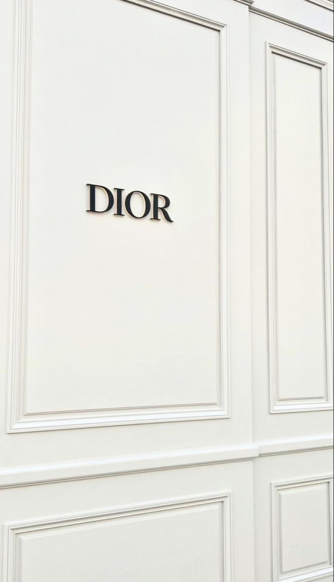 the word dior is written in black on a white paneled wall with doors