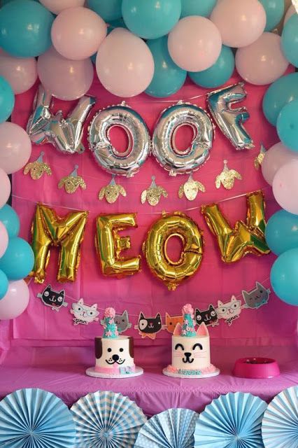 a table topped with lots of balloons and cake next to a sign that says woof meow