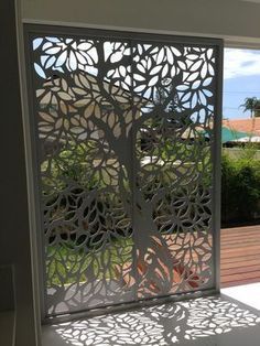 an open window with laser cut screens on the outside, and wooden deck in the background