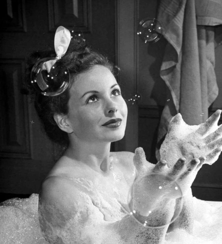 a woman in a white dress is holding soap bubbles and looking up at the sky