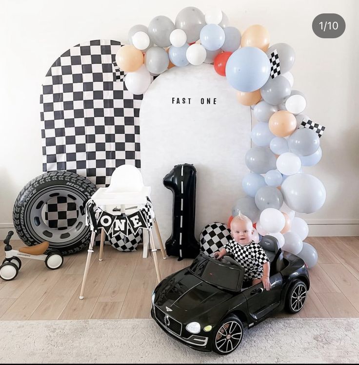 a baby in a toy car is surrounded by balloons