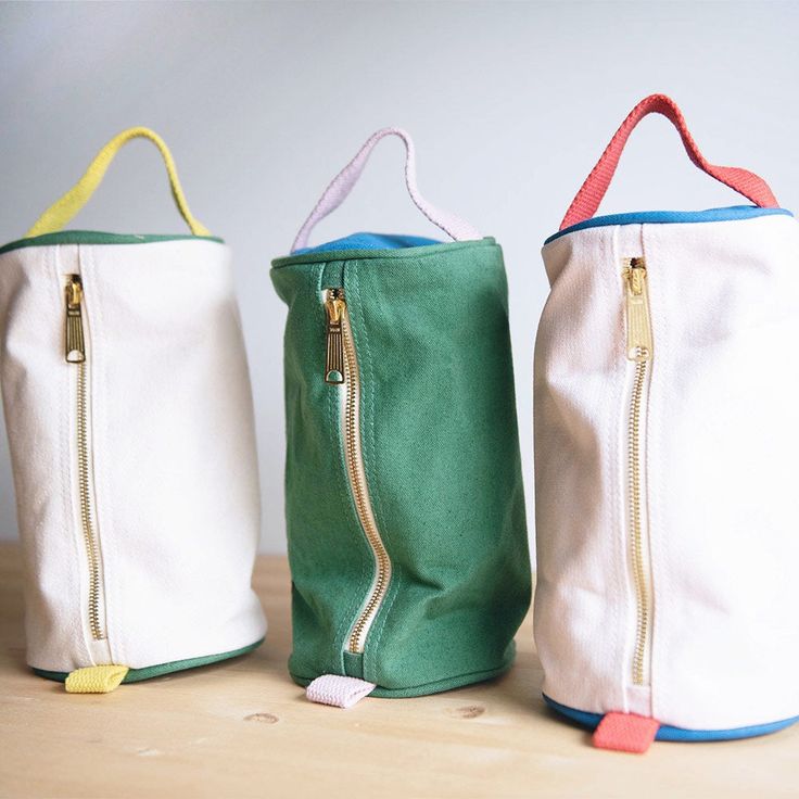 three zippered bags sitting on top of a wooden table