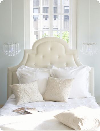 a bed with white linens and pillows in a bedroom next to a large window