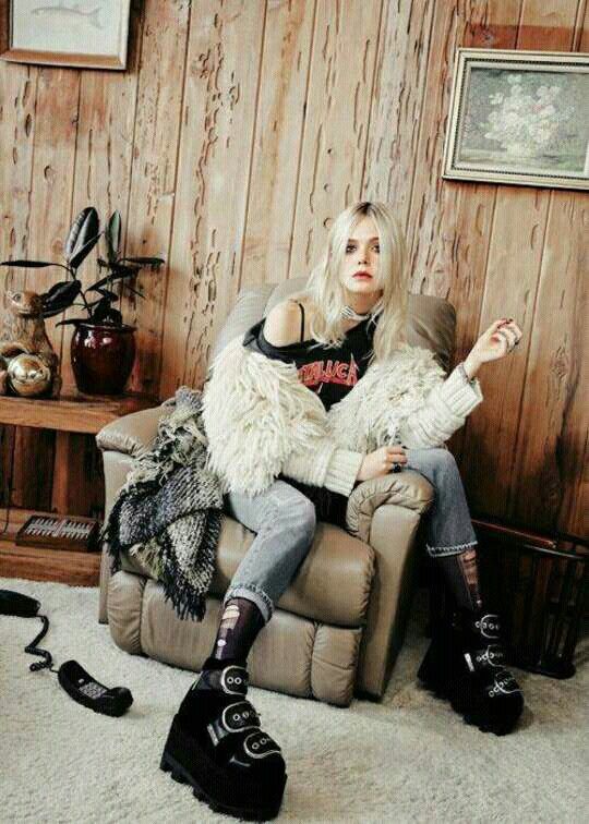 a woman sitting on top of a chair in a living room next to a wooden wall