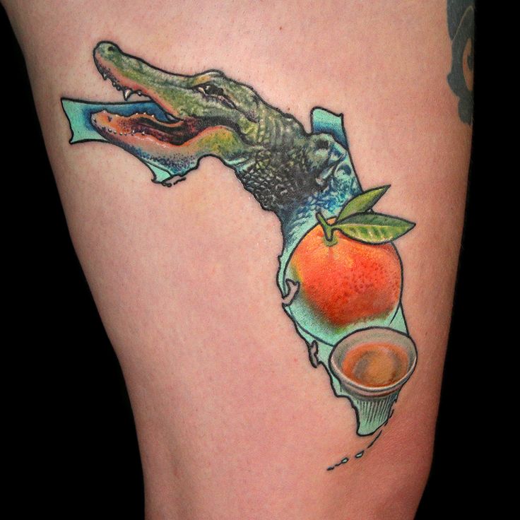 a tattoo on the leg of a woman with an orange and alligator's head