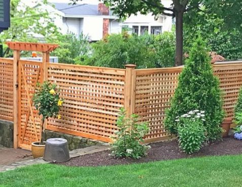 a wooden fence in the middle of a yard with potted plants next to it