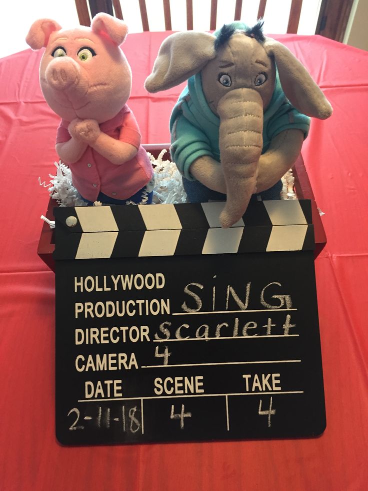 two stuffed animals sit on top of a clapper board at a movie theater table