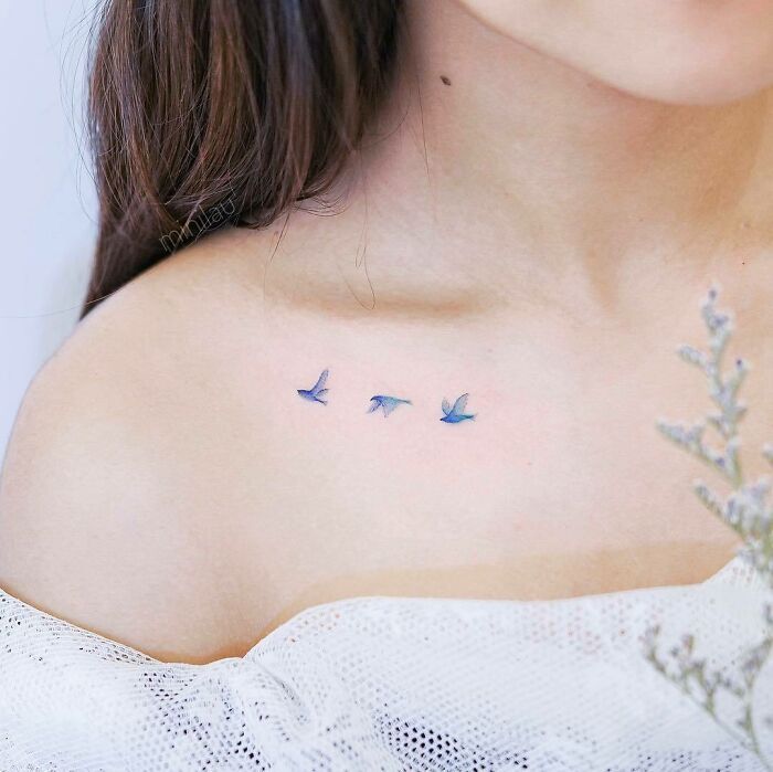 a woman's chest with three birds tattoo on her left shoulder and the word love written in small letters