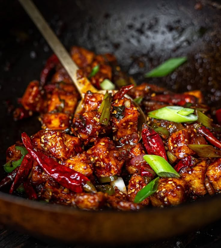 some food is being cooked in a wok with chopsticks on the side