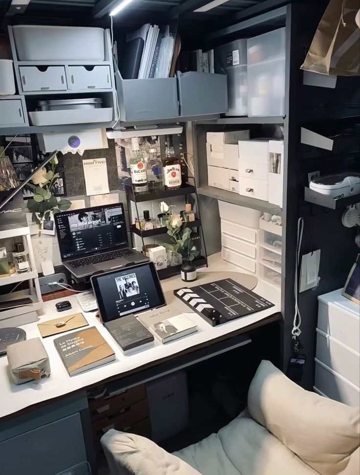 a desk with laptops and other items on it in a room filled with drawers