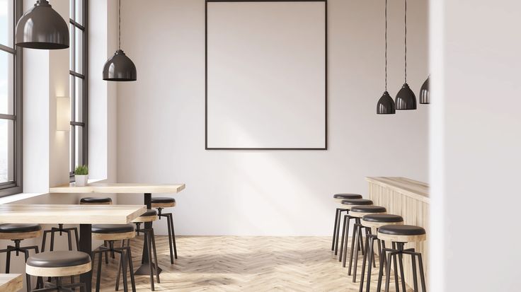 an empty restaurant with tables and stools in front of a large poster hanging on the wall