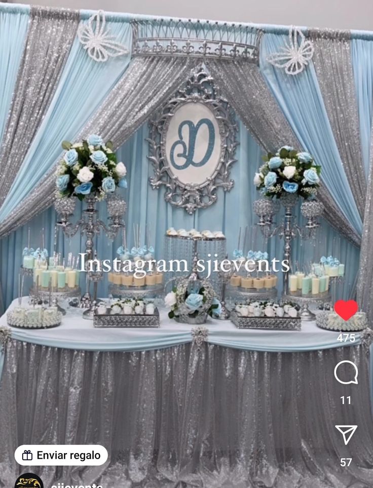 a table topped with cakes and cupcakes under a blue drape covered backdrop