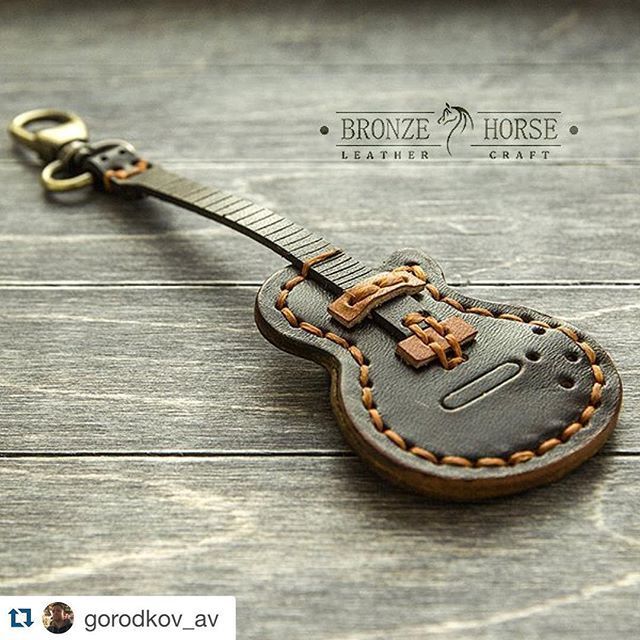 a guitar shaped keychain is shown on a wooden surface with the name bronze horse