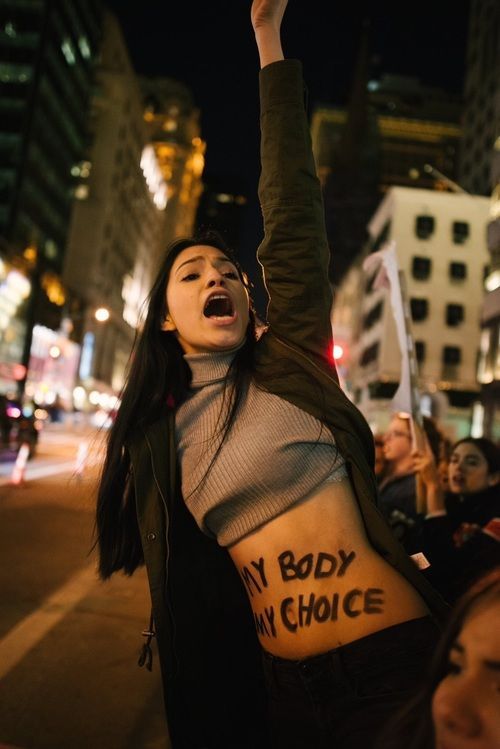 a woman with her arms up in the air and writing on her stomach that says, my body is my choice