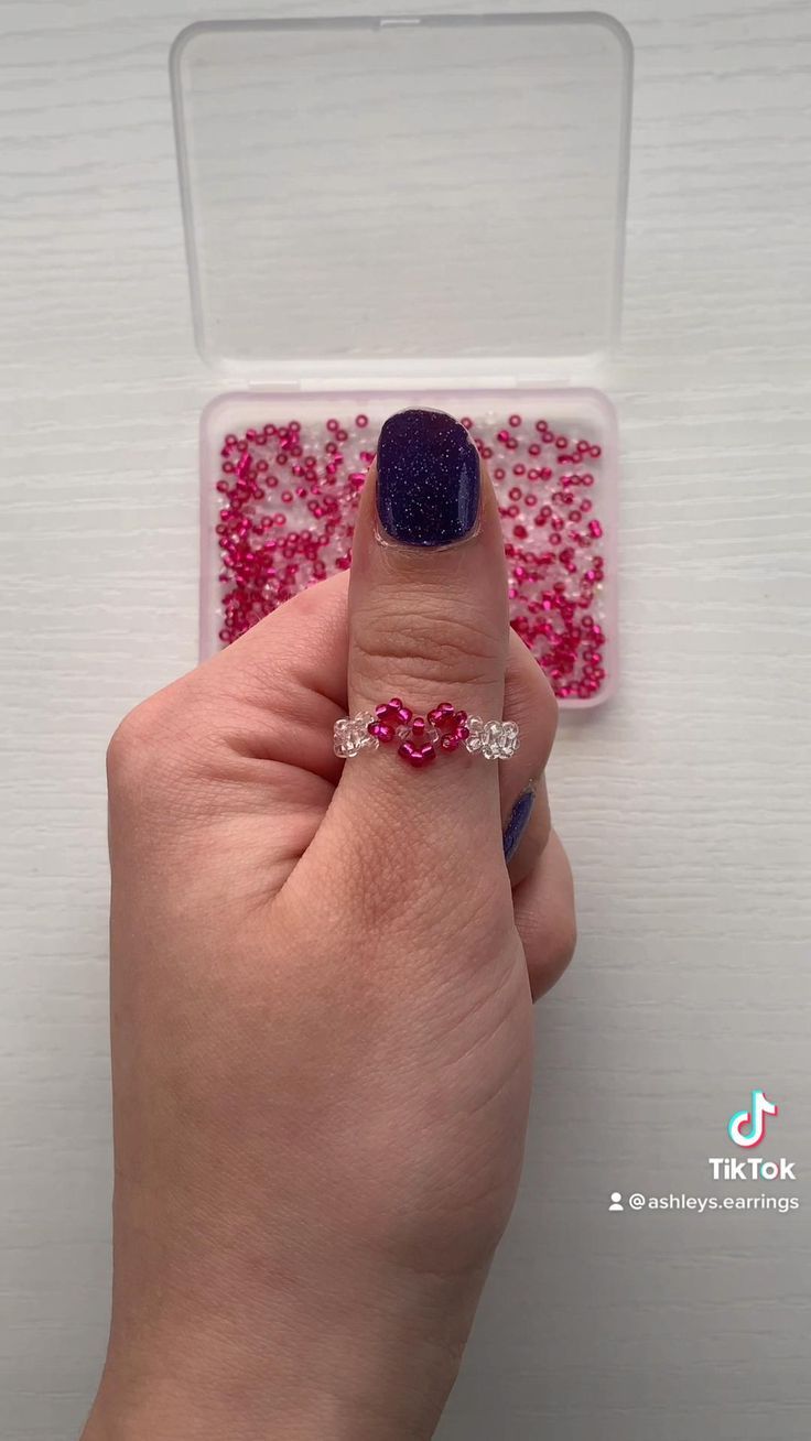 a woman's hand holding a ring with pink and red sprinkles