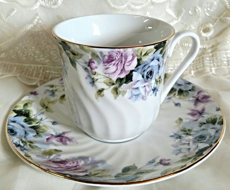 a cup and saucer sitting on top of a white table cloth covered tablecloth