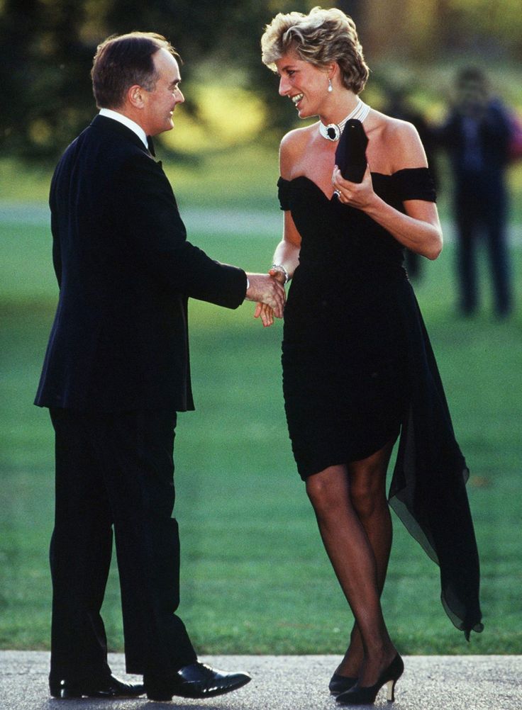 a woman in a black dress shaking hands with a man