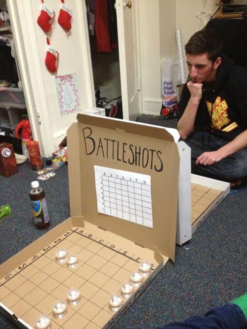 a man sitting on the floor next to a box with candles in it that says battleshots