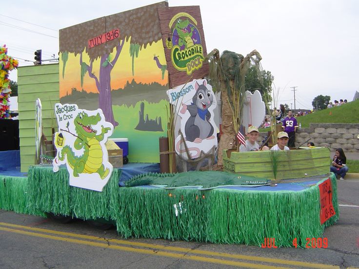 the float is decorated in green grass and features pictures of cartoon characters on it's sides