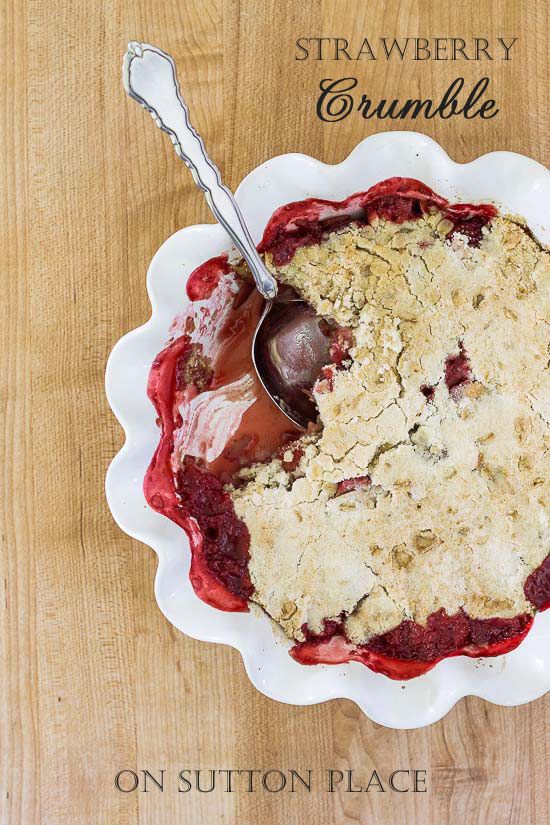 a strawberry crumble pie in a white dish with a spoon on the side and text overlay that reads, strawberry crumble