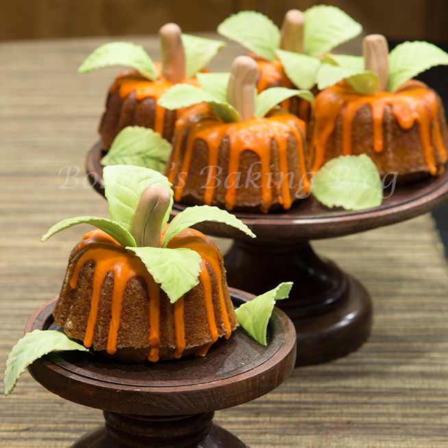 small cakes with green leaves and caramel drizzled on top are sitting on wooden pedestals