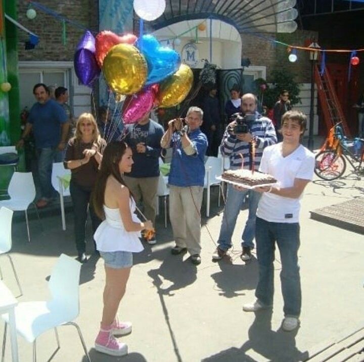 a group of people standing around each other with balloons in the shape of heart shapes