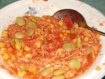 a white plate topped with lots of food on top of a green table next to a wooden spoon