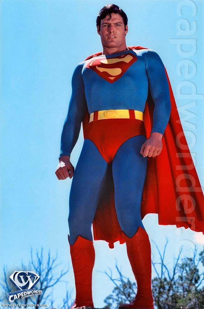 a man dressed as superman standing in front of a blue sky