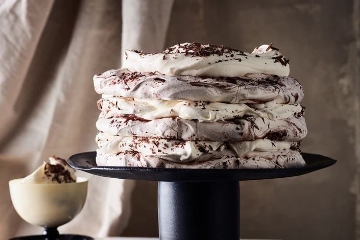 a stack of cake sitting on top of a black platter next to a cup