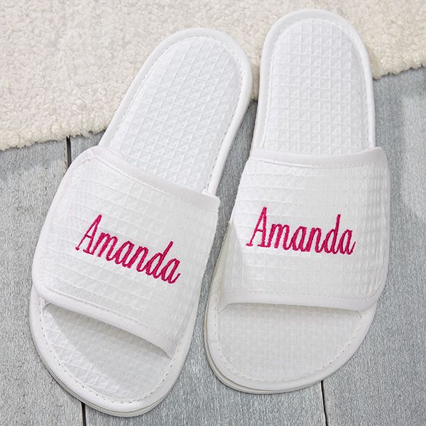 white slippers with the word amanda written in red on them sitting on a wooden floor