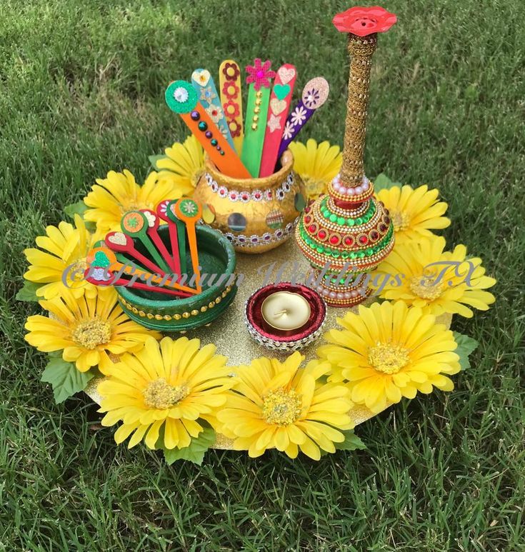 there are many items on the table in the grass with flowers around them and candles