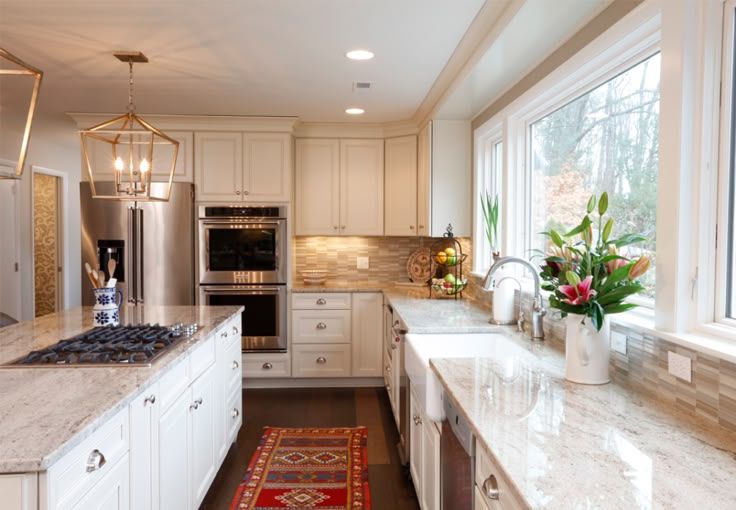 a large kitchen with white cabinets and marble counter tops, along with an area rug on the floor