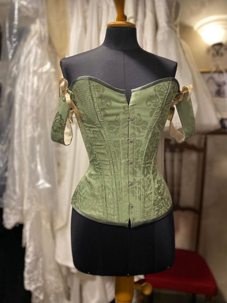 Green overbust corset with cording panels and detachable straps, made in apple green silk brocade and cream woven cotton lining. This corset is meant to be worn to emphasise the classic hourglass silhouette. Offers up to 10 cm waist reduction.  Plastic boning and metal busk.  This beauty is available in a number of different colours and fabrics and completely customisable, message me for more details! MEASUREMENTS: This item is available to be made to order, you must provide me with the followin Fitted Corset With Boning For Costume, Fitted Bodice Corset With Boning For Costume, Wedding Overbust Corset With Boning, Fitted Overbust Corset With Boning, Formal Overbust Corset Dress With Boned Bodice, Elegant Costume Corset With Boning, Overbust Corset With Boning And Fitted Bodice, Elegant Corset With Historical Design For Costume Party, Fitted Overbust Corset Dress With Bust Darts