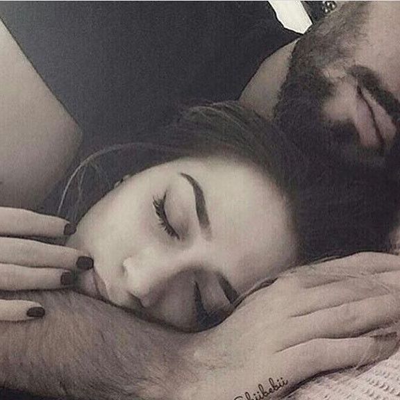 a man and woman are cuddling together on the bed with their eyes close to each other