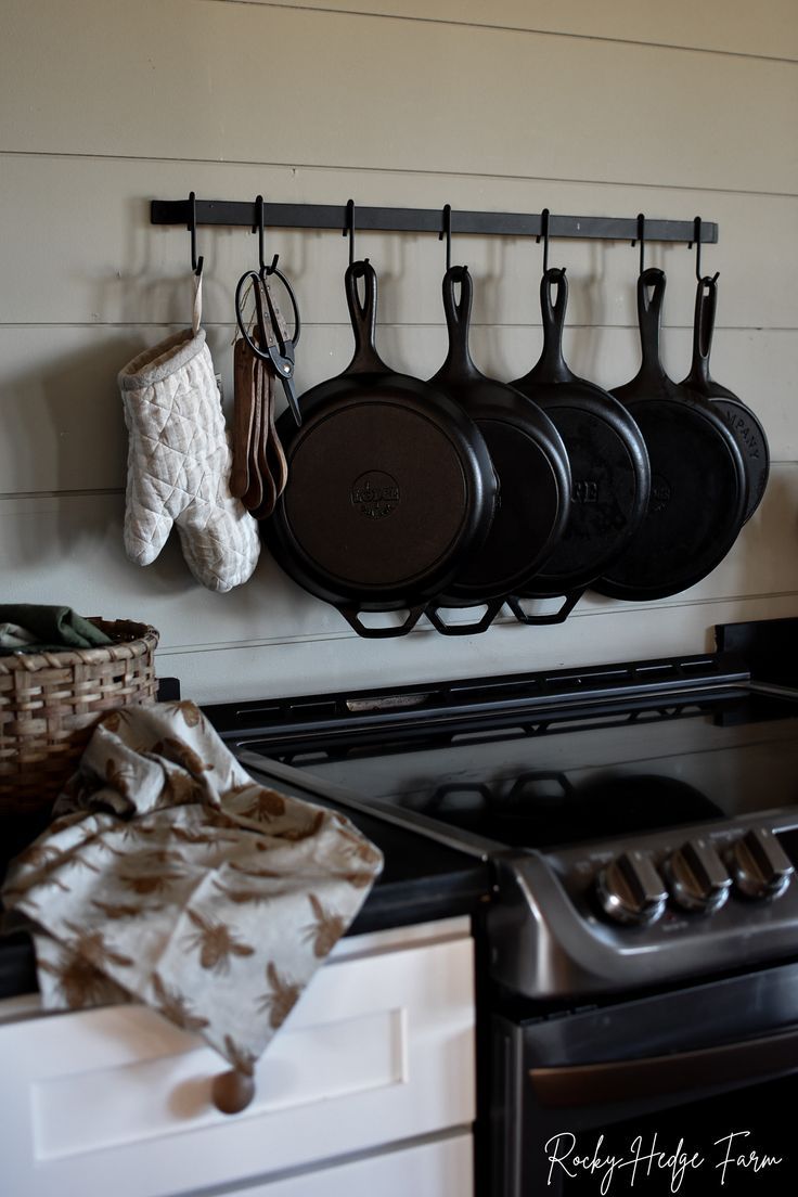 pots and pans are hanging on the wall above an oven with two mitts