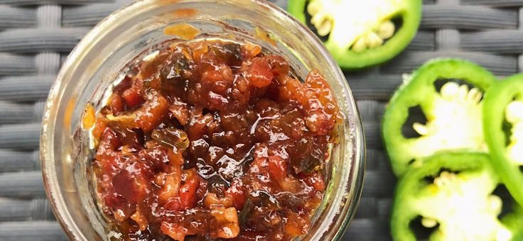 a glass jar filled with food next to sliced jalapenos