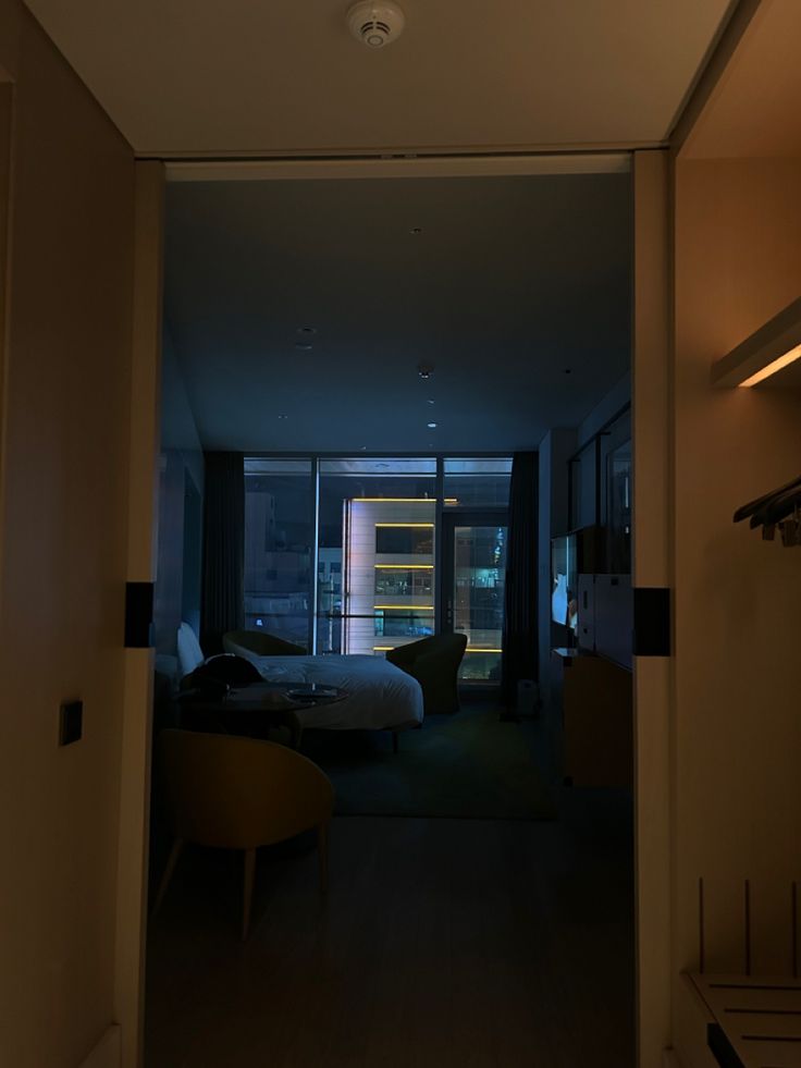 an open door leading to a bedroom with a bed and desk in the background at night