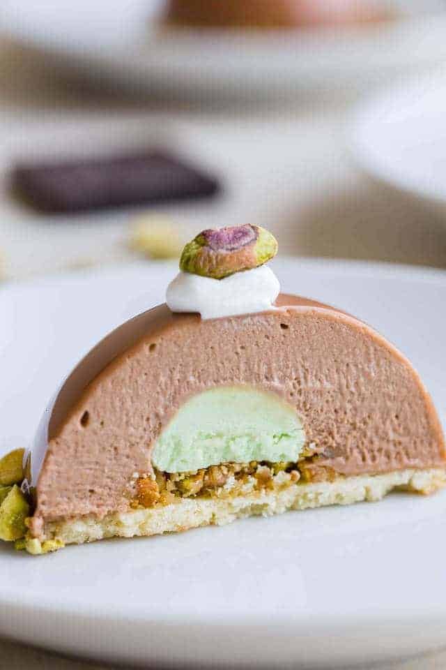 a piece of pie with whipped cream and pistachio on top sits on a white plate