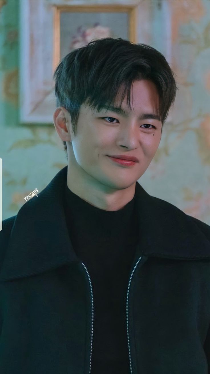 the young man is smiling and looking at the camera while wearing a black jacket with zippers on it