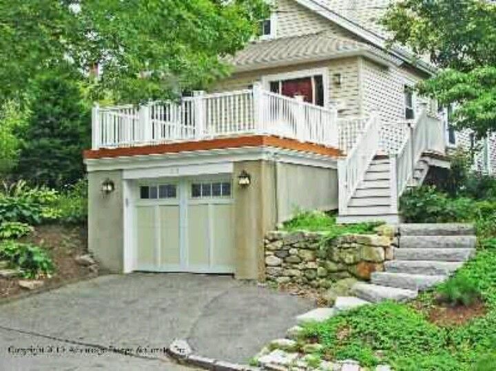 a garage with stairs leading up to the second floor and an attached deck above it