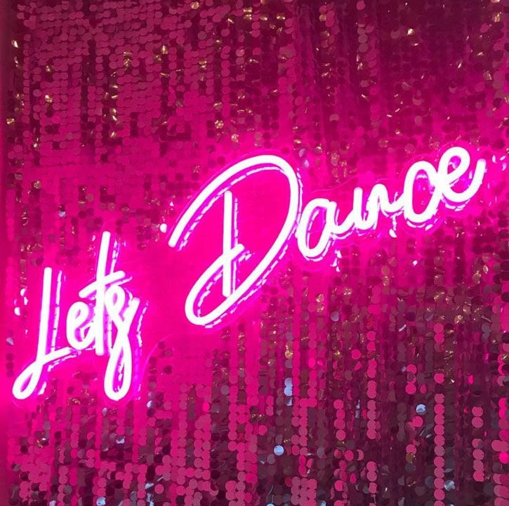 a neon sign that says let's dance on the side of a wall with sequins