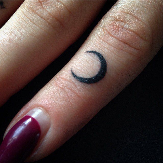 a woman's finger with a crescent tattoo on it