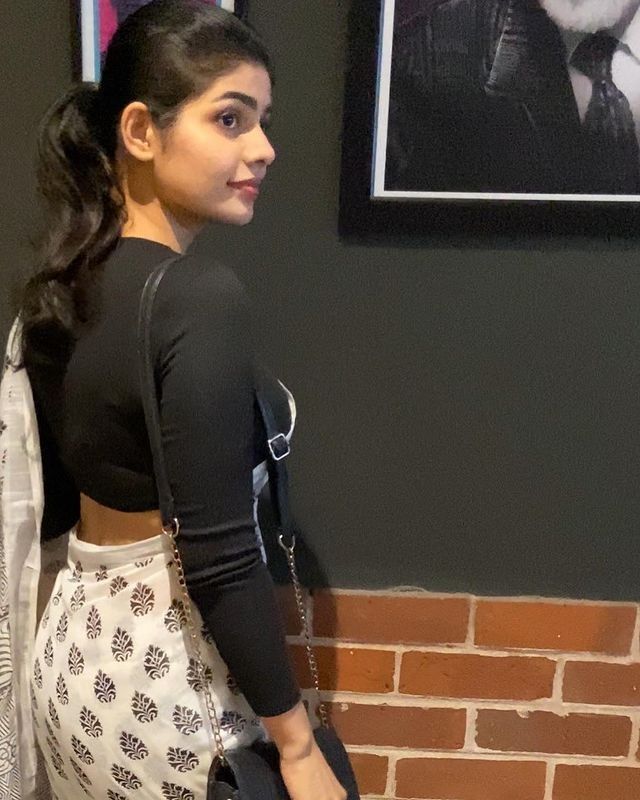 a woman standing in front of a brick wall with her back turned to the camera