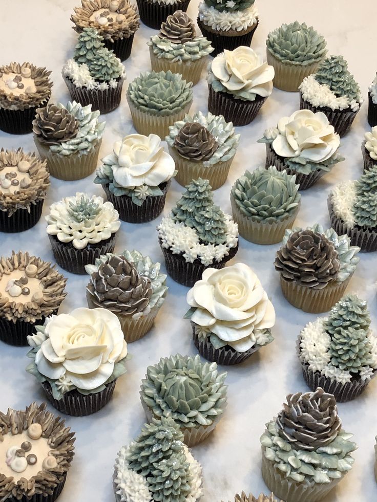 cupcakes decorated with flowers and succulents are arranged on a table