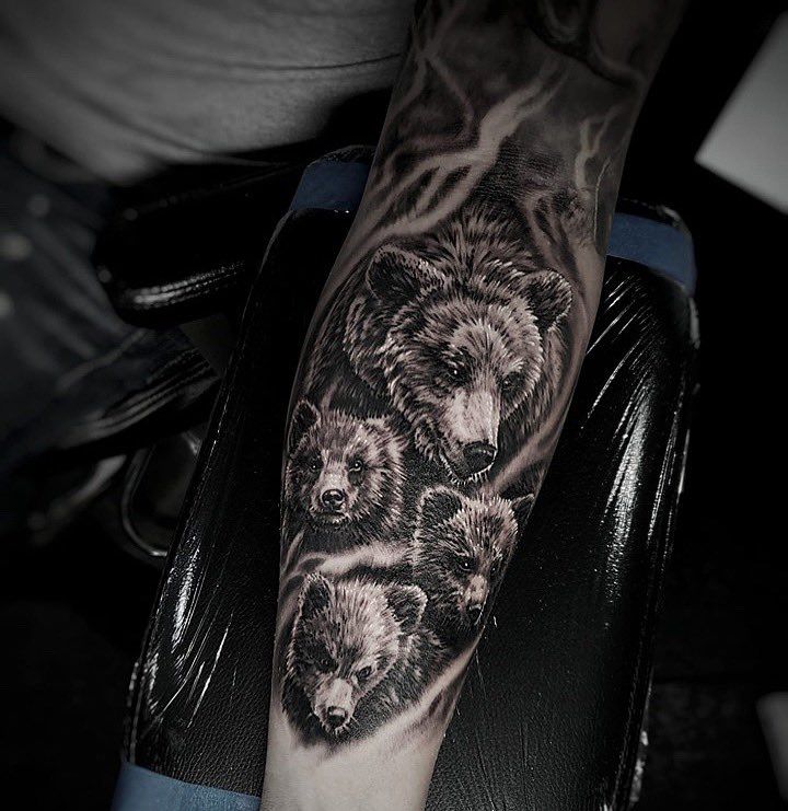 a man with a bear tattoo on his arm is holding a black and white photo