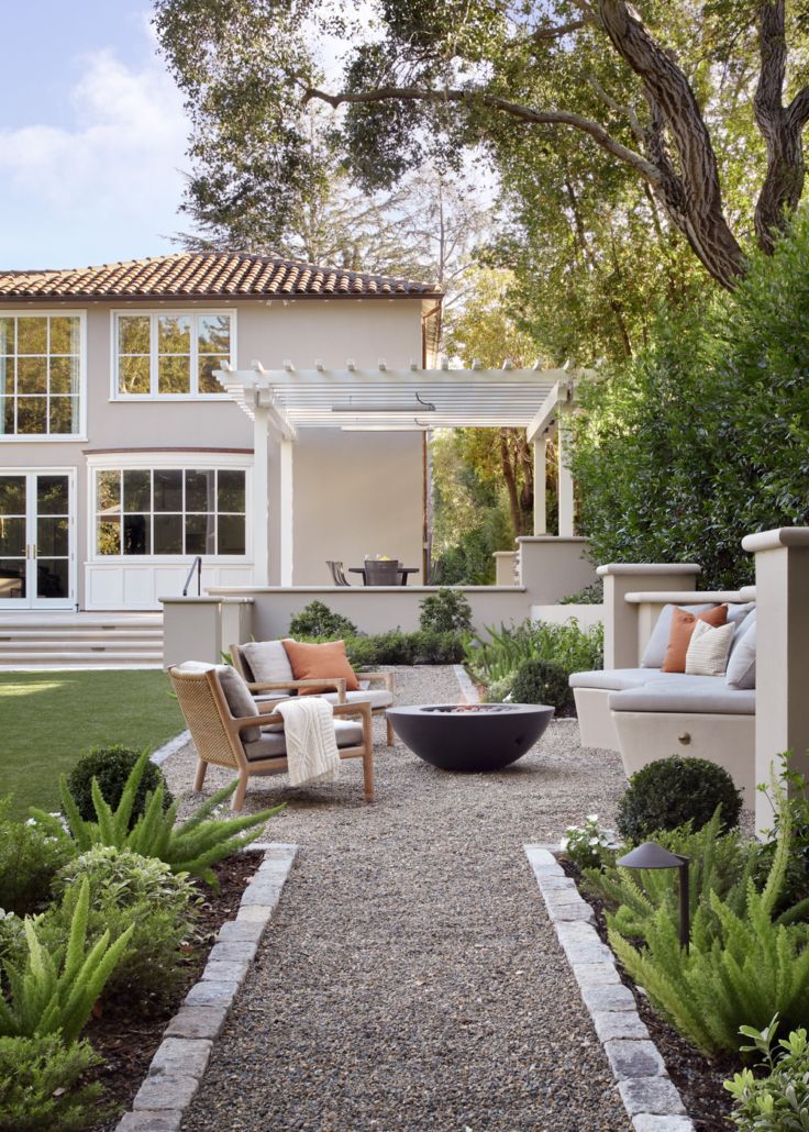 an outdoor living area with chairs, couches and fire pit in front of a house