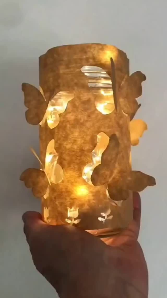 a hand holding a lit up jar with lights on it's sides and wings