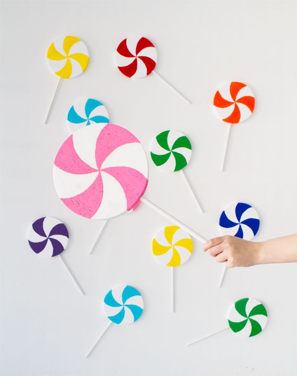 colorful lollipops are being held by a person's hand on a white background