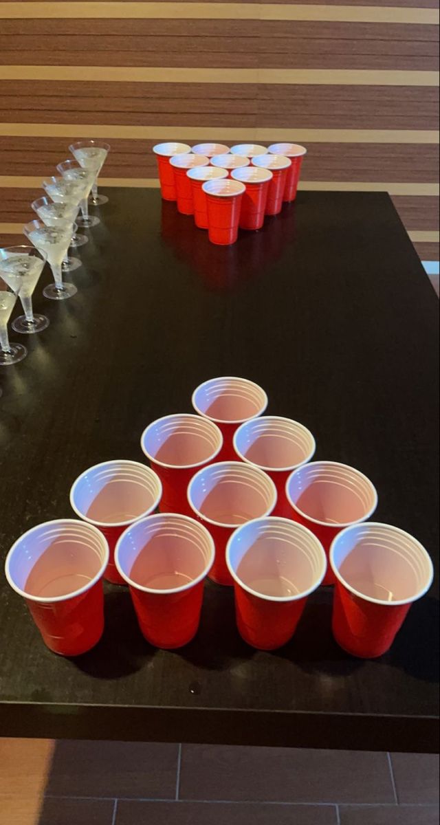 red cups are arranged on a black table with plastic cups in the shape of a triangle