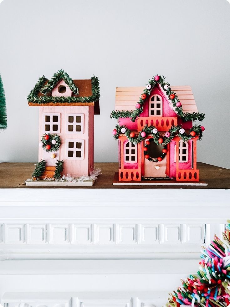 two christmas houses on top of a mantle